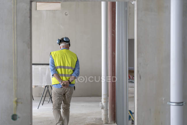 Trabajador de la construcción en edificio incompleto, vista trasera - foto de stock