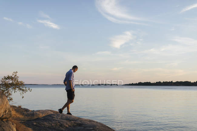 Homme marchant sur le rocher par la mer — Photo de stock