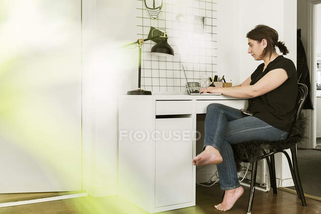 Junge Frau benutzt Laptop am Schreibtisch — Stockfoto