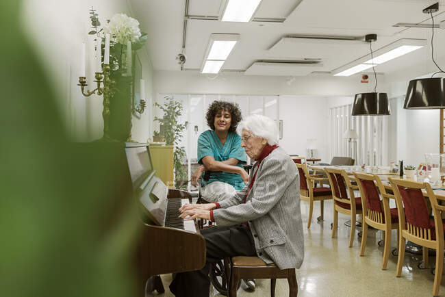 Donna anziana che suona il pianoforte in casa di riposo — Foto stock