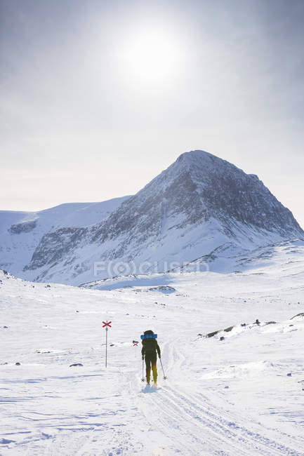 Mujer esquiando por marcadores en el sendero Kungsleden en Laponia, Suecia - foto de stock