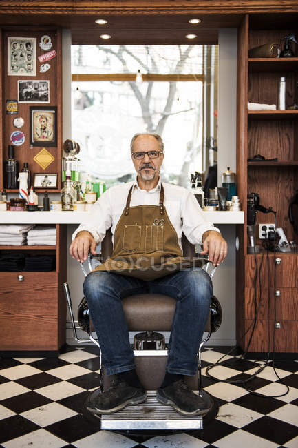 Barbeiro sentado na cadeira na barbearia, foco seletivo — Fotografia de Stock