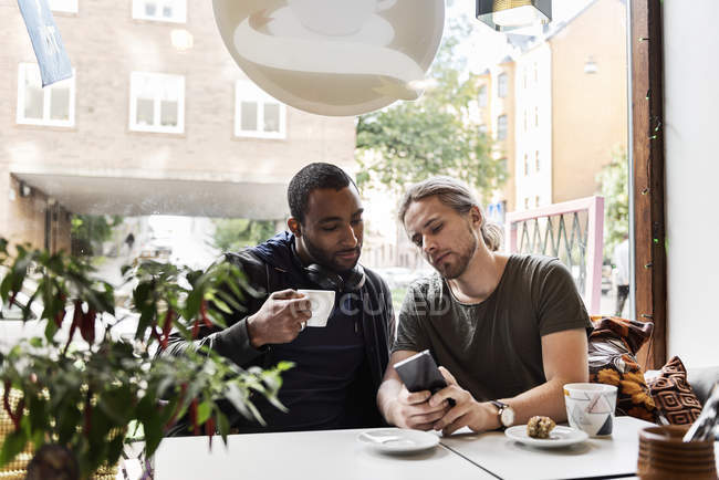 Jóvenes sentados juntos en la cafetería - foto de stock