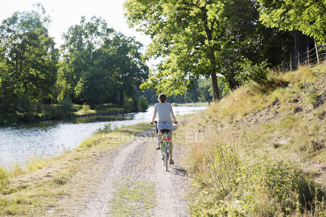 Mulher ciclismo por canal, vista traseira — Fotografia de Stock