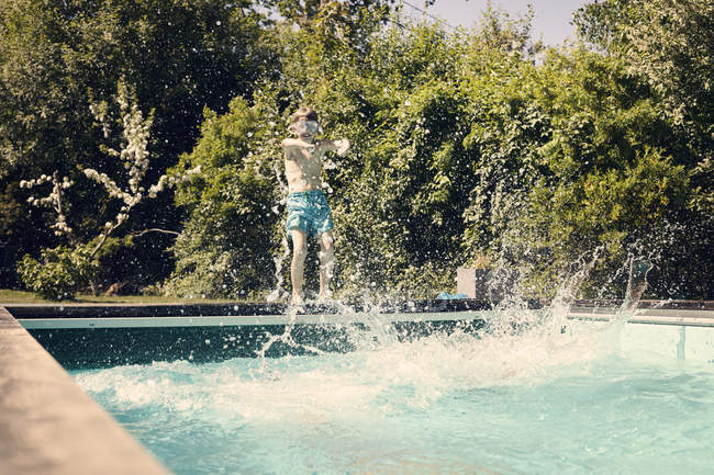 Хлопчик перед басейном з бризкою водою — стокове фото