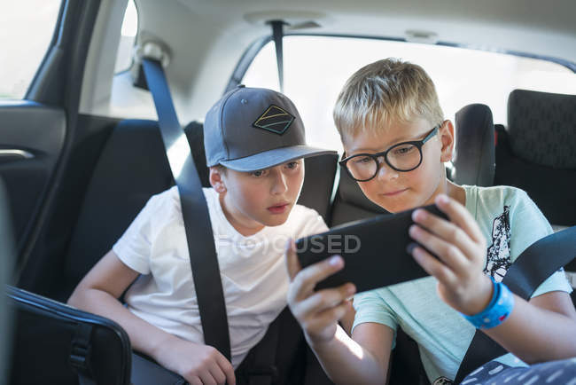Boys con teléfono inteligente en coche, enfoque selectivo. - foto de stock