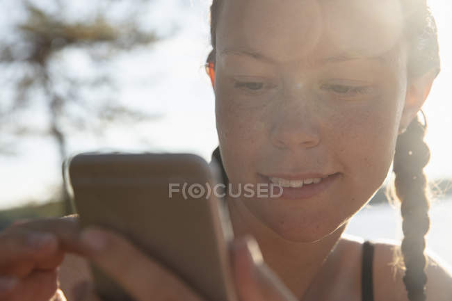 Jovem mulher usando telefone inteligente, foco em primeiro plano — Fotografia de Stock