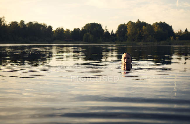 Женщина купается в озере и смотрит в камеру — стоковое фото