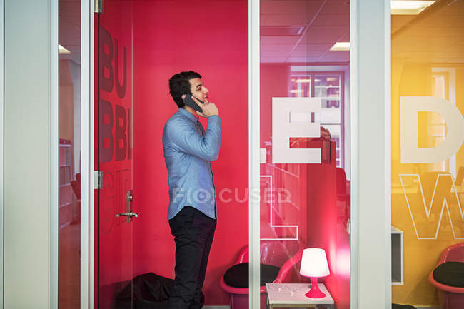 Молодой человек разговаривает по телефону в офисе — стоковое фото