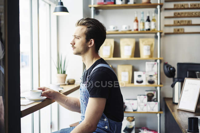 Young man drinking coffee in cafe, selective focus — Stock Photo