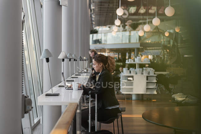 Mujer usando el ordenador portátil en el aeropuerto, enfoque selectivo - foto de stock