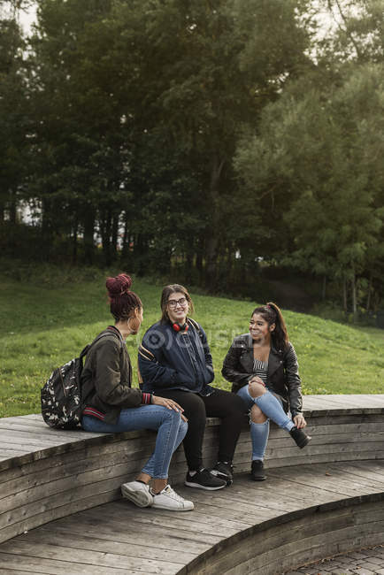 Teenage girls sitting on bench in park — Stock Photo