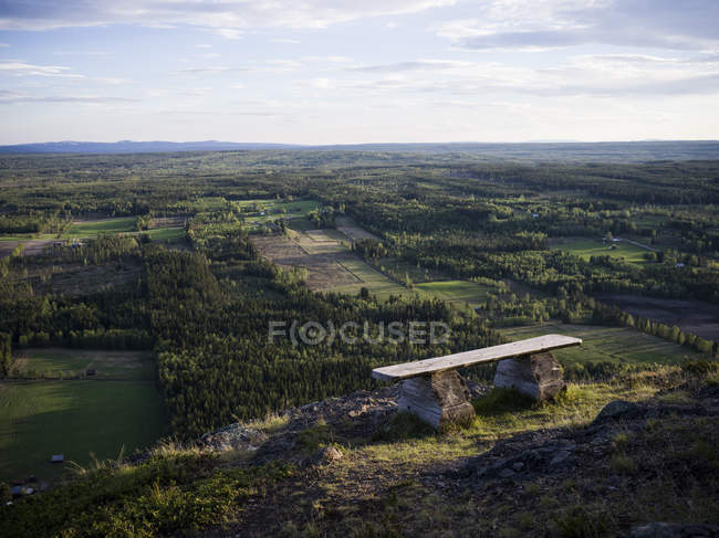 Scenic view of bench on hill overlooking farmland — Stock Photo