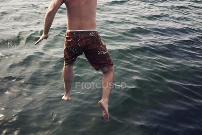 Человек, прыгающий в море, избирательный фокус — стоковое фото