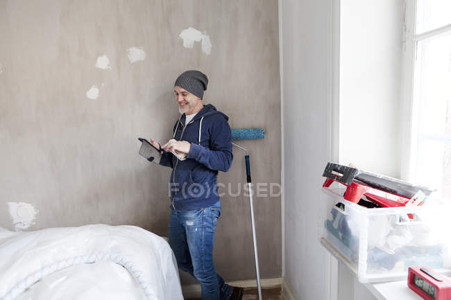 Homme adulte moyen regardant tablette PC pendant la rénovation de l'appartement — Photo de stock