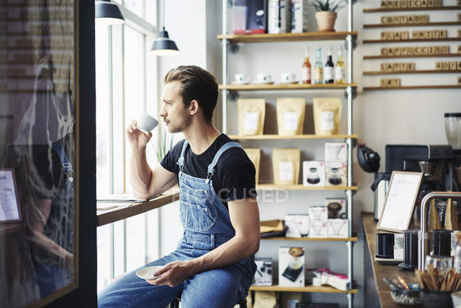 Молодий чоловік п'є каву в кафе, вибірковий фокус — стокове фото