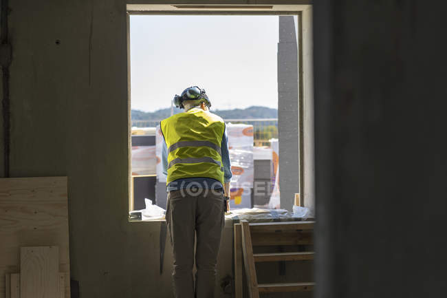 Ouvrier de la construction par fenêtre de bâtiment incomplet — Photo de stock