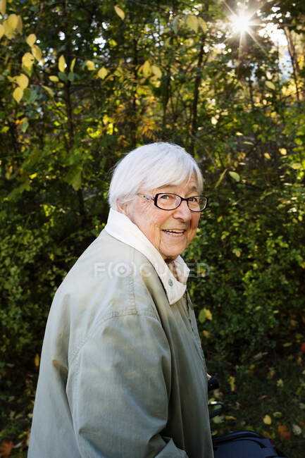 Anziana che cammina nel parco e sorride di macchina fotografica — Foto stock
