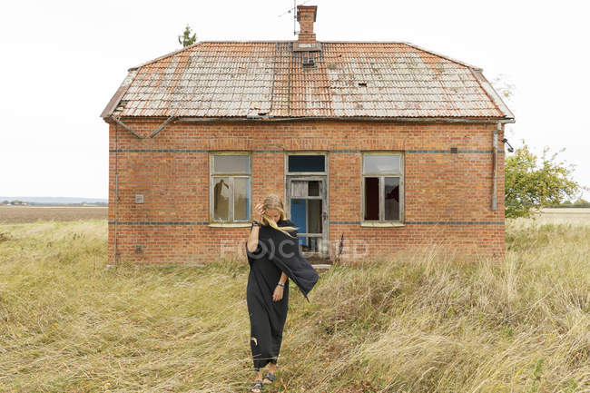 Mujer vestida de negro por casa abandonada - foto de stock