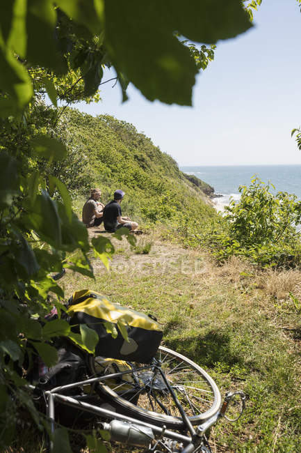 Мужчины сидят на траве на велосипеде — стоковое фото