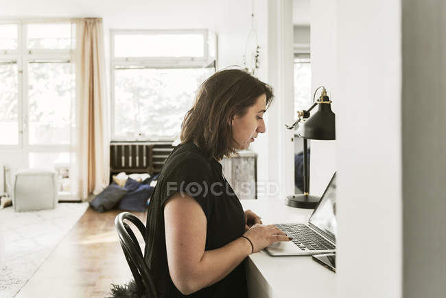 Молодая женщина с ноутбуком за столом — стоковое фото