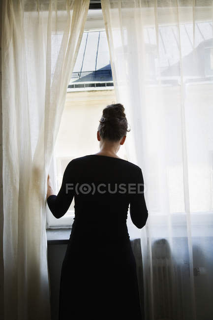 Frau blickt durch Fenster, selektiver Fokus — Stockfoto