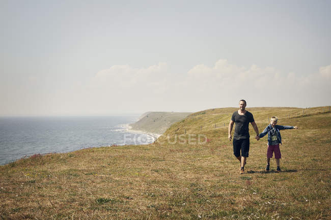 Uomo e ragazzo sulla collina vicino al mare — Foto stock