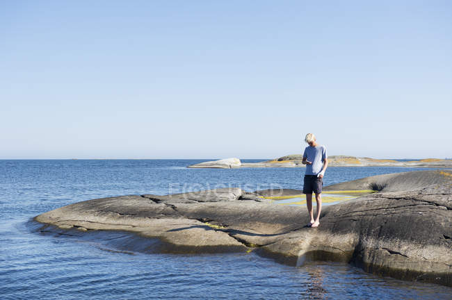 Молодий чоловік стоїть на скелях біля моря — стокове фото