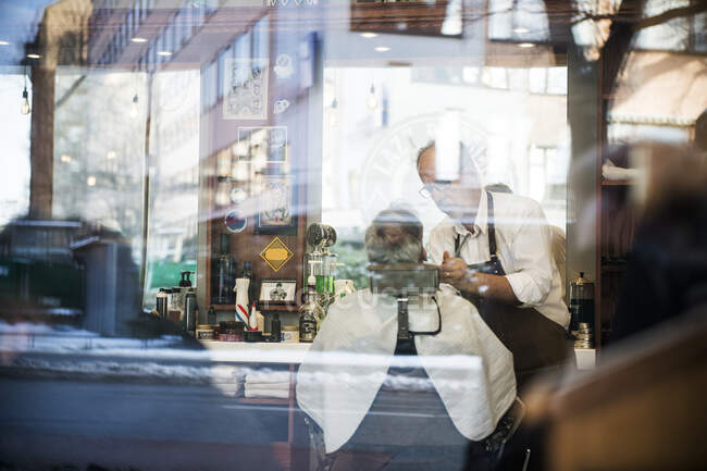 Blick durch das Fenster des Friseurs, der den Kunden die Haare schneidet — Stockfoto