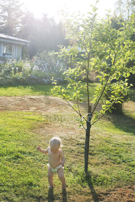 Menina no gramado por árvores, foco seletivo — Fotografia de Stock