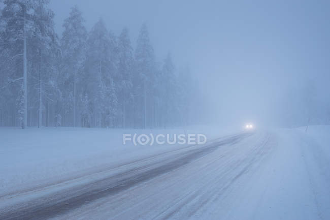 Faróis na estrada coberta de neve — Fotografia de Stock