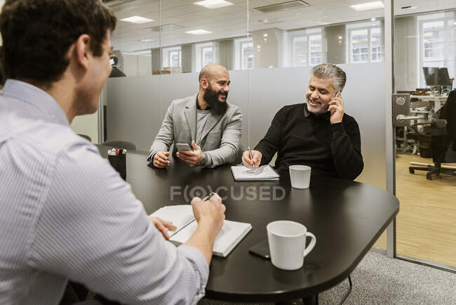 Hommes discutant de projet lors d'une réunion d'affaires au bureau — Photo de stock