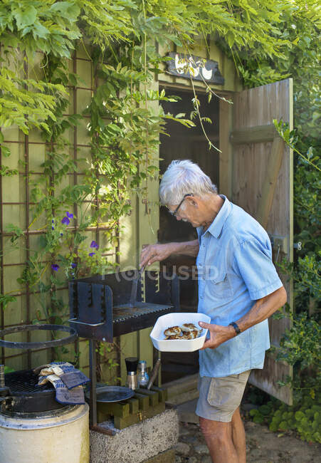 Anziani che utilizzano barbecue nel cortile — Foto stock