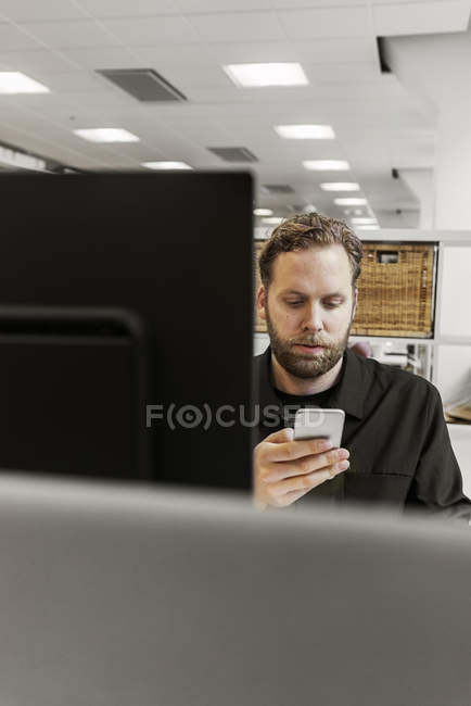 Uomo che utilizza lo smart phone alla scrivania — Foto stock