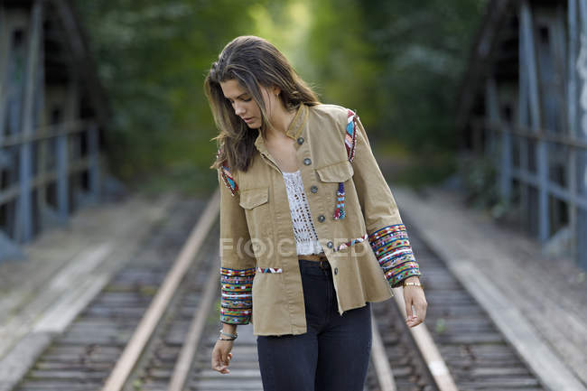 Teenage girl wearing jacket on train tracks — Stock Photo