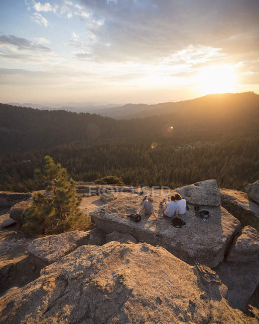 Hombres en roca al atardecer en el Parque Nacional Sequoia en California - foto de stock