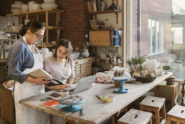 Женщины используют ноутбук в мастерской по керамике — стоковое фото