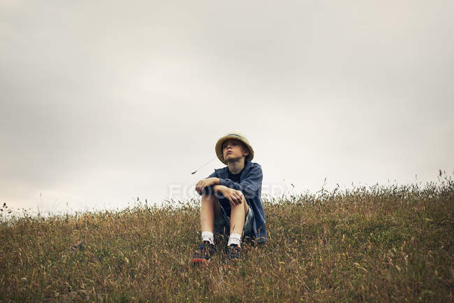 Мальчик сидит на холме, избирательный фокус — стоковое фото