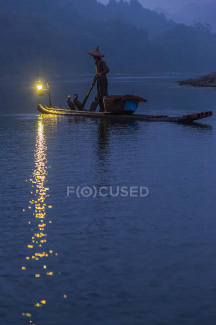 Чоловік веслував на плоті в сутінках у провінції Сичуань (Китай). — стокове фото