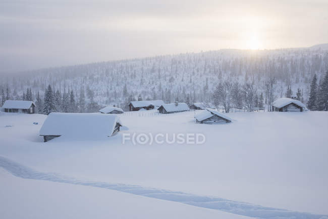 Cabanes en rondins recouvertes de neige — Photo de stock