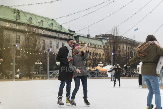 Casal tomando selfie enquanto patinação no gelo, foco seletivo — Fotografia de Stock