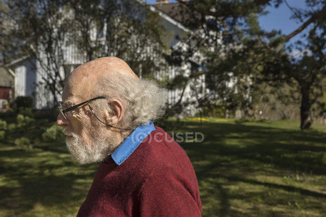 Profile of senior man in yard, selective focus — Stock Photo