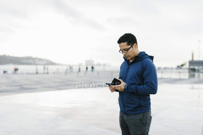 Man using smart phone in town square — Stock Photo