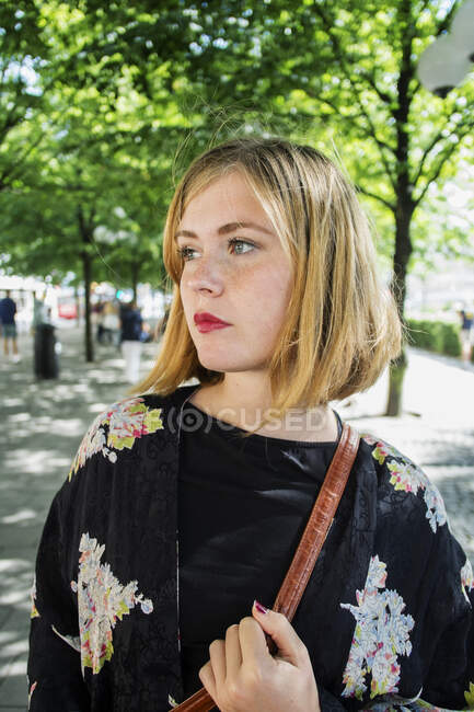 Jovem mulher olhando de lado enquanto caminhava na cidade — Fotografia de Stock