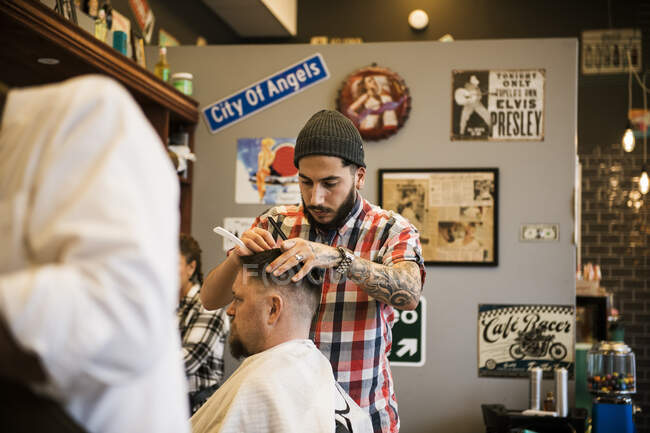 Barber cutting customer hair in barbershop — Stock Photo