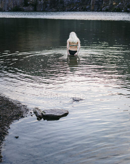 Une adolescente nage dans une rivière, vue de l'arrière — Photo de stock