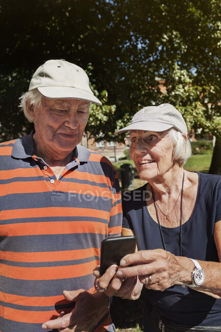Retrato de parejas mayores felices de pie juntas al aire libre en un día soleado. - foto de stock