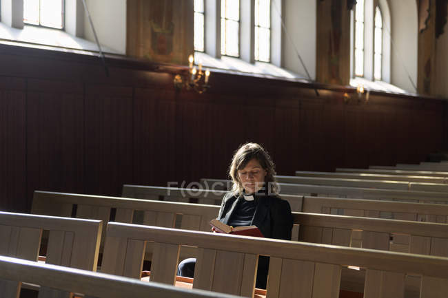 Priest reading bible on church pew, selective focus — Stock Photo