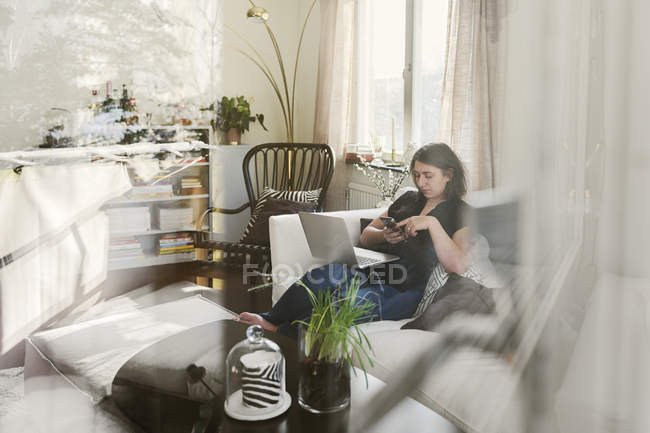 Молода жінка використовує ноутбук на дивані, вибірковий фокус — стокове фото