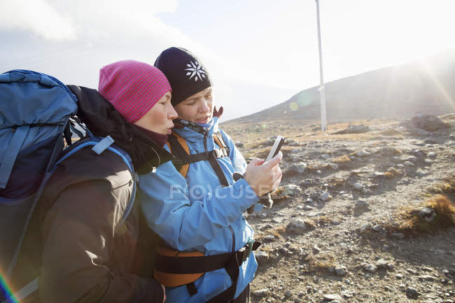 Las mujeres que utilizan el teléfono inteligente durante la caminata, enfoque selectivo - foto de stock
